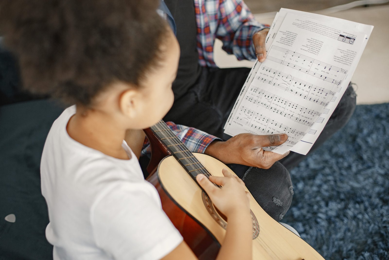 Father with daughter on couch. Girl holding a guitar. Learning guitar.